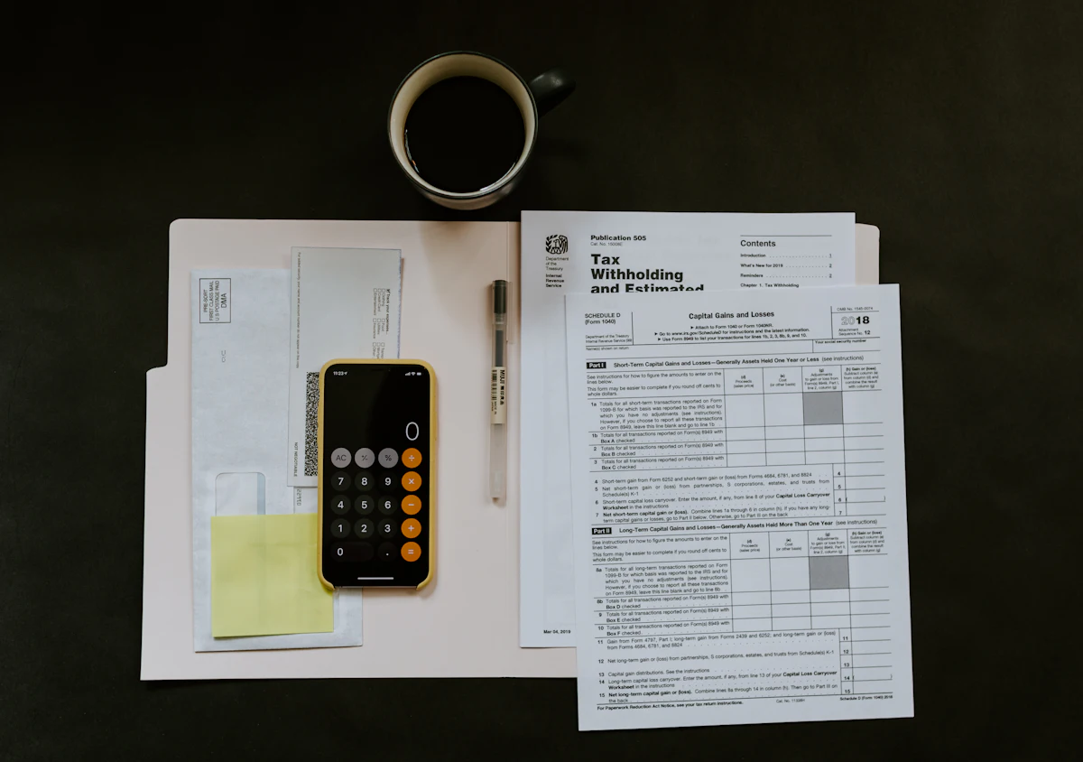 Tax forms, a calculator, and a cup of coffee on a desk